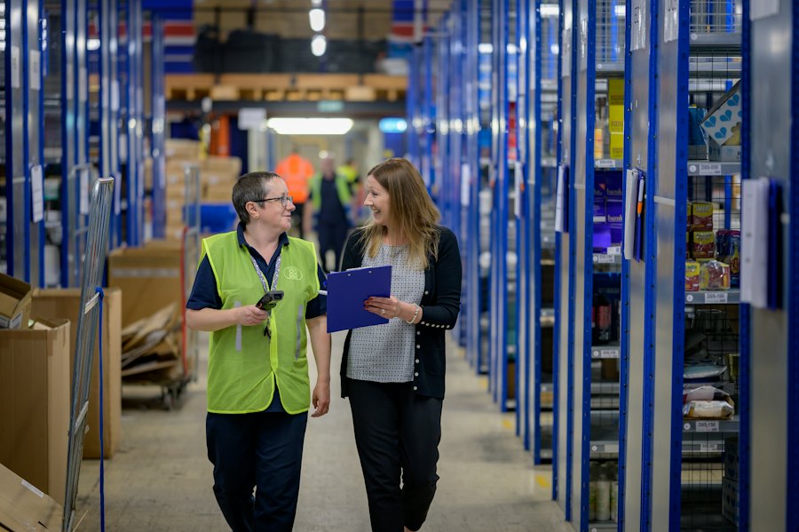 Warehouse staff reviewing inventory between shelving aisles